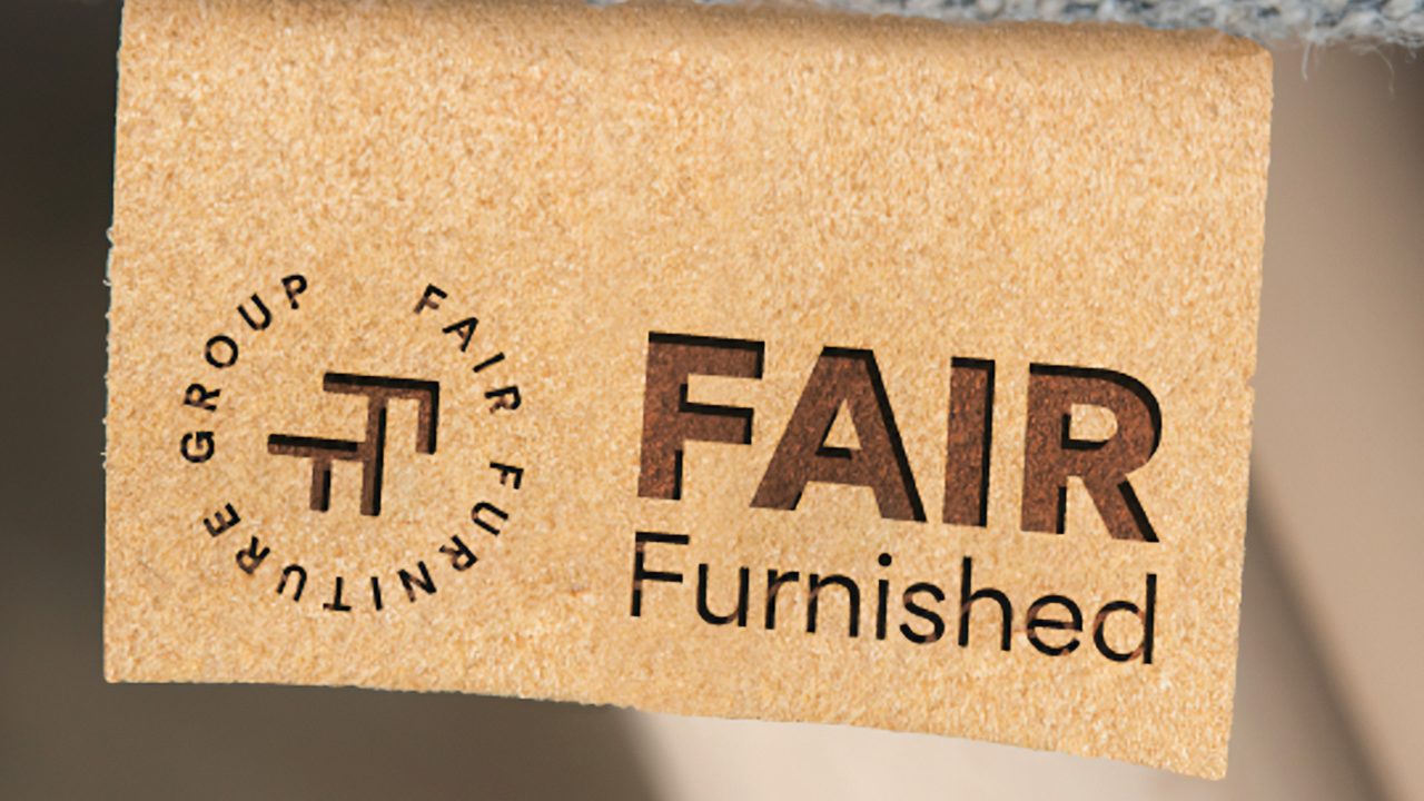 Leren label met het logo van Fair Furniture Group op een meubel met lichtblauwe stof